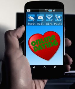 Online Dating app on smartphone, being held up by a hand
