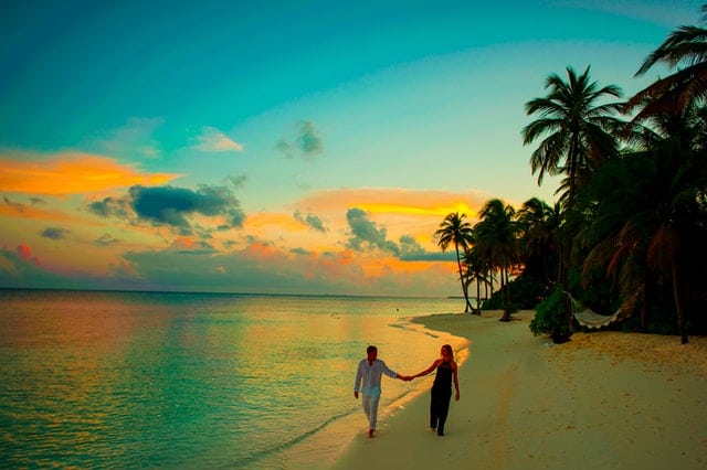 Couple holding hands in the evening walking on the beach of a Tropical Island