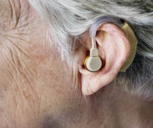 Old white woman with close up of her ear with hearing aid