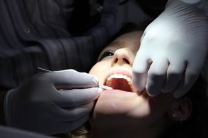 Young Woman with mouth open being examined by a dentist with a spotlight on her face