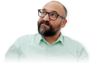 Middle-aged man in round black-rimmed glasses, with short black beard and light-green shirt looking upwards in a pensive expression on his face.