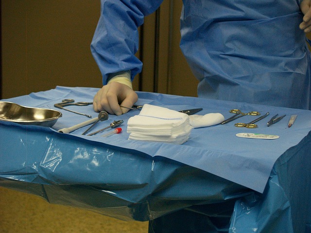 Table with surgical instruments - a large pile of wire gauze and silver kidney dish with surgeon