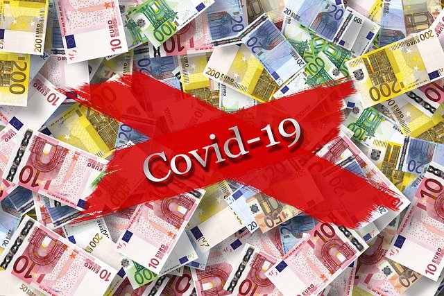 Covid 19 emblazoned with a bright red "X" over Euro Bills in assorted denominations in a randomly scattered background.