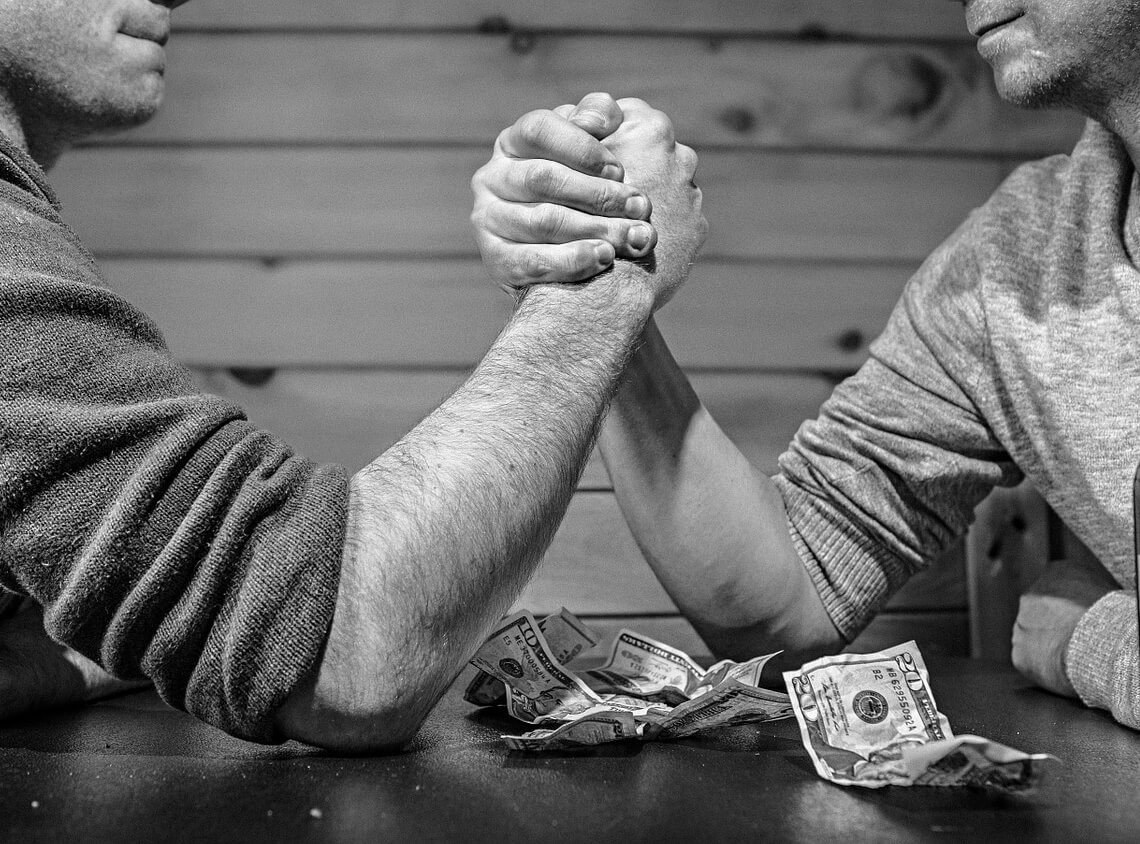 Two strong men, arm-wrestling over crunched up dollar bills (black and white western)