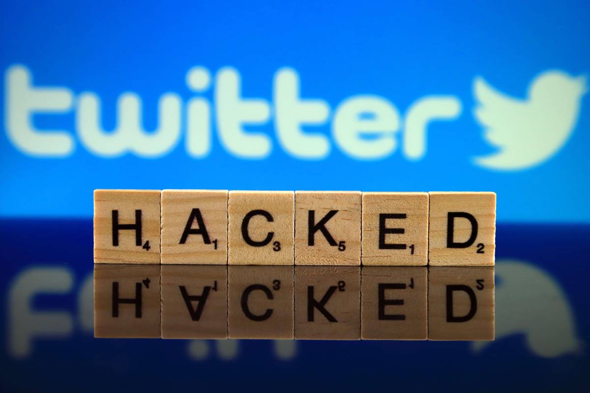 Twitter Logo int he background, with scrabble pieces spelling "HACKED" in the foreground