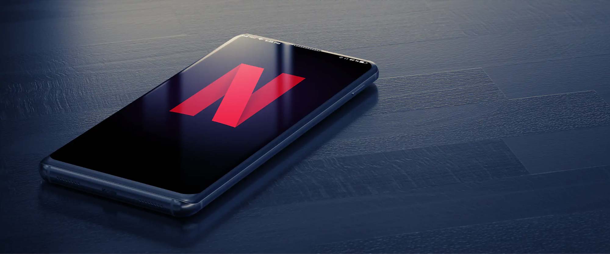 Netflix red logo on iPhone X resting on dark-blue wooden surface