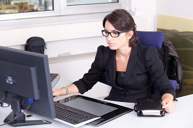 Young woman executive working on a desktop computer in an office and holding a daily-planner.