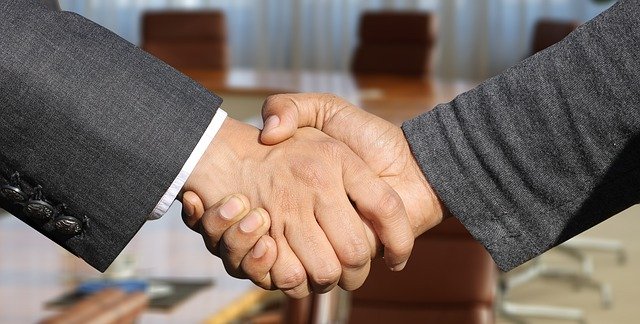 Two business men shaking hands in an empty board room with the camera focused on just their hands.